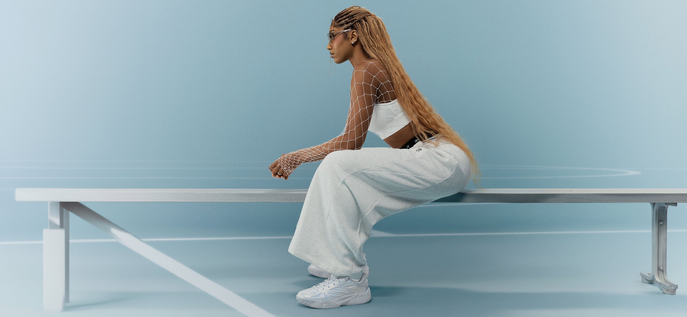 Person sitting on a white bench against a light blue background