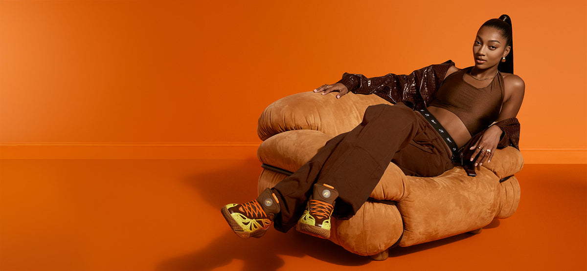 woman wearing brown outfit wearing orange, yellow and brown basketball shoes 