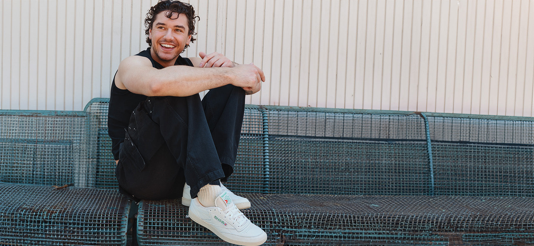 Person sitting on a metal bench with a textured wall background