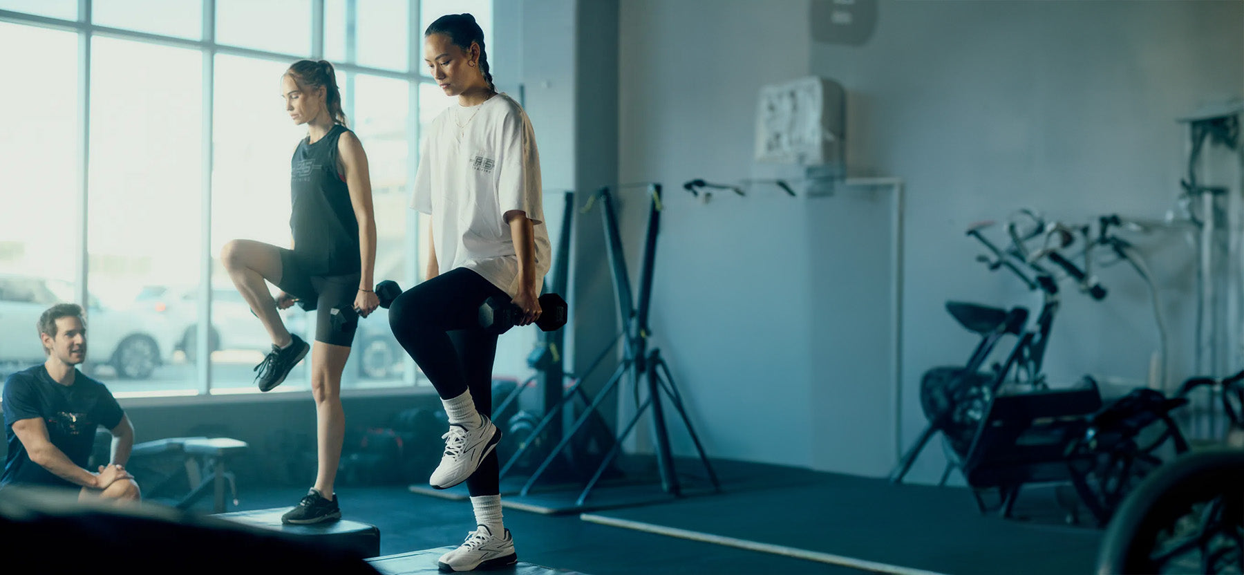 2 women working out with weights in a gym 