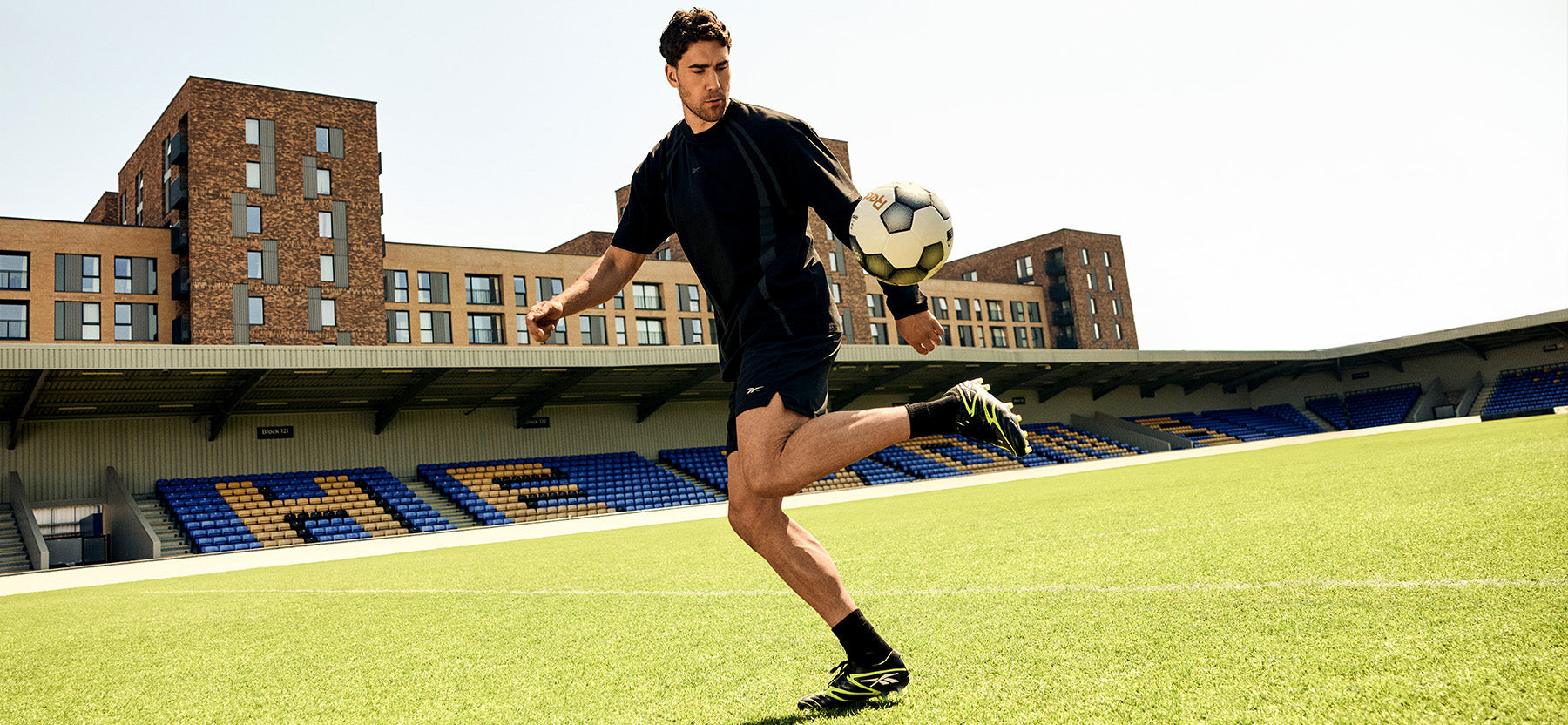 Person playing soccer on a field with stadium seats in the background