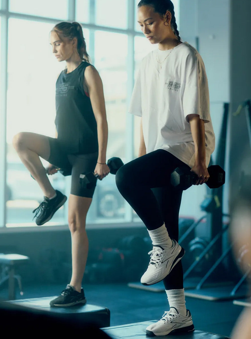 2 women working out with weights in a gym 
