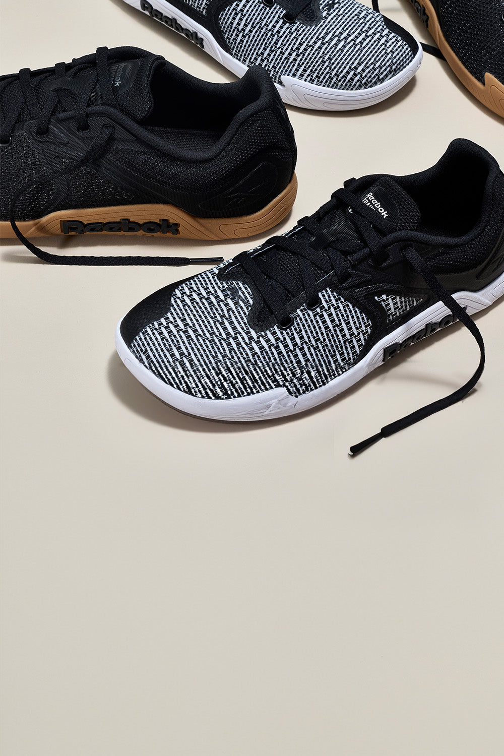 Black and white athletic shoes with Reebok branding on a beige background