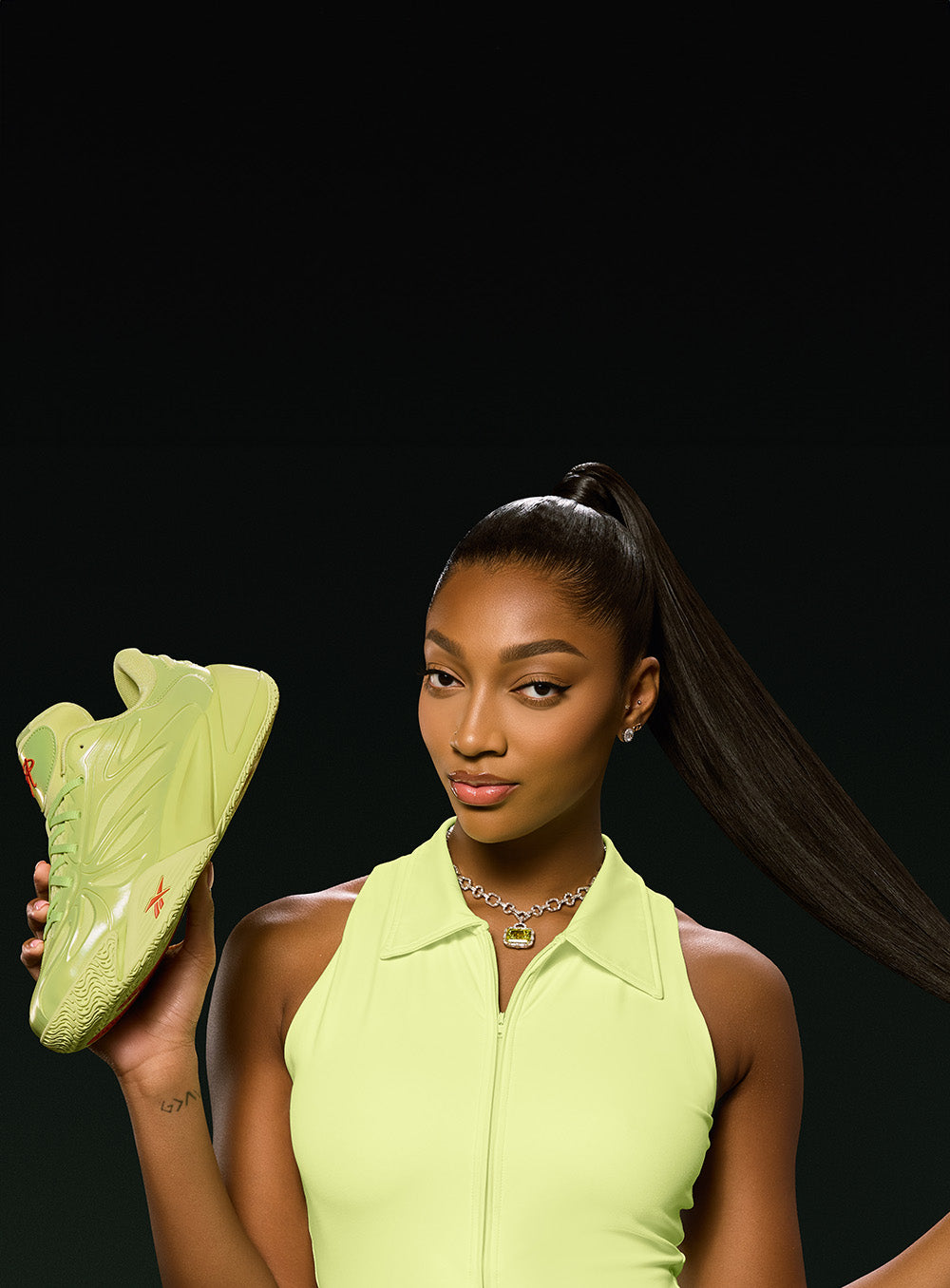 Woman holding a green sneaker against a black background