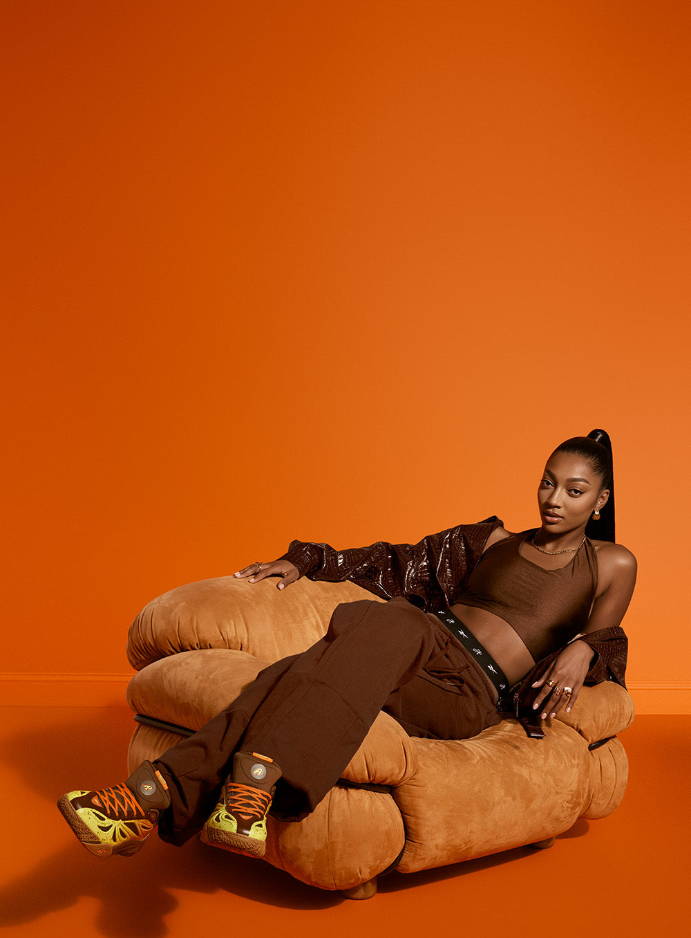 woman wearing brown outfit wearing orange, yellow and brown basketball shoes 