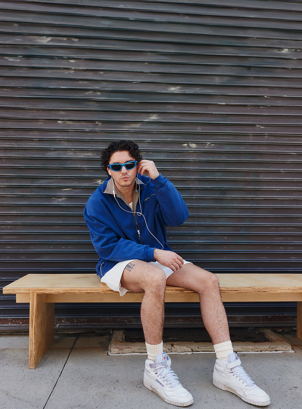 man sitting on bench wearing white reebok shoes