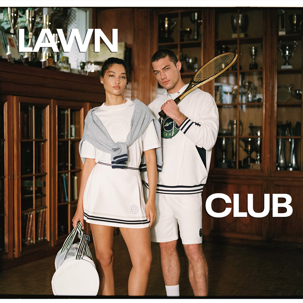 Two people in tennis attire standing in a room with trophies, holding a racket and a bag, with 'Lawn Club' text.