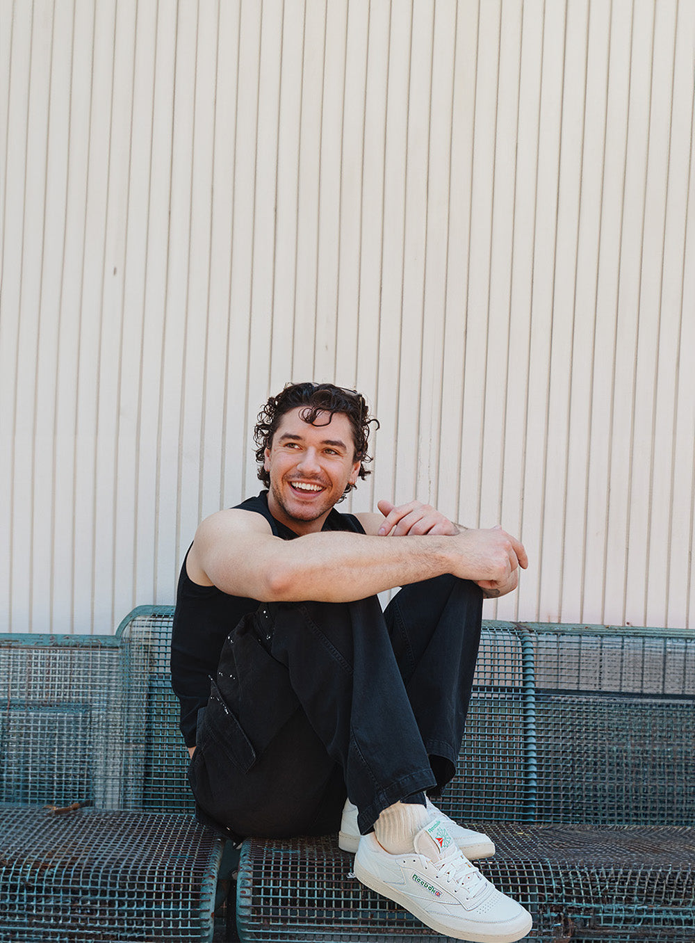 Man sitting on a bench against a textured wall
