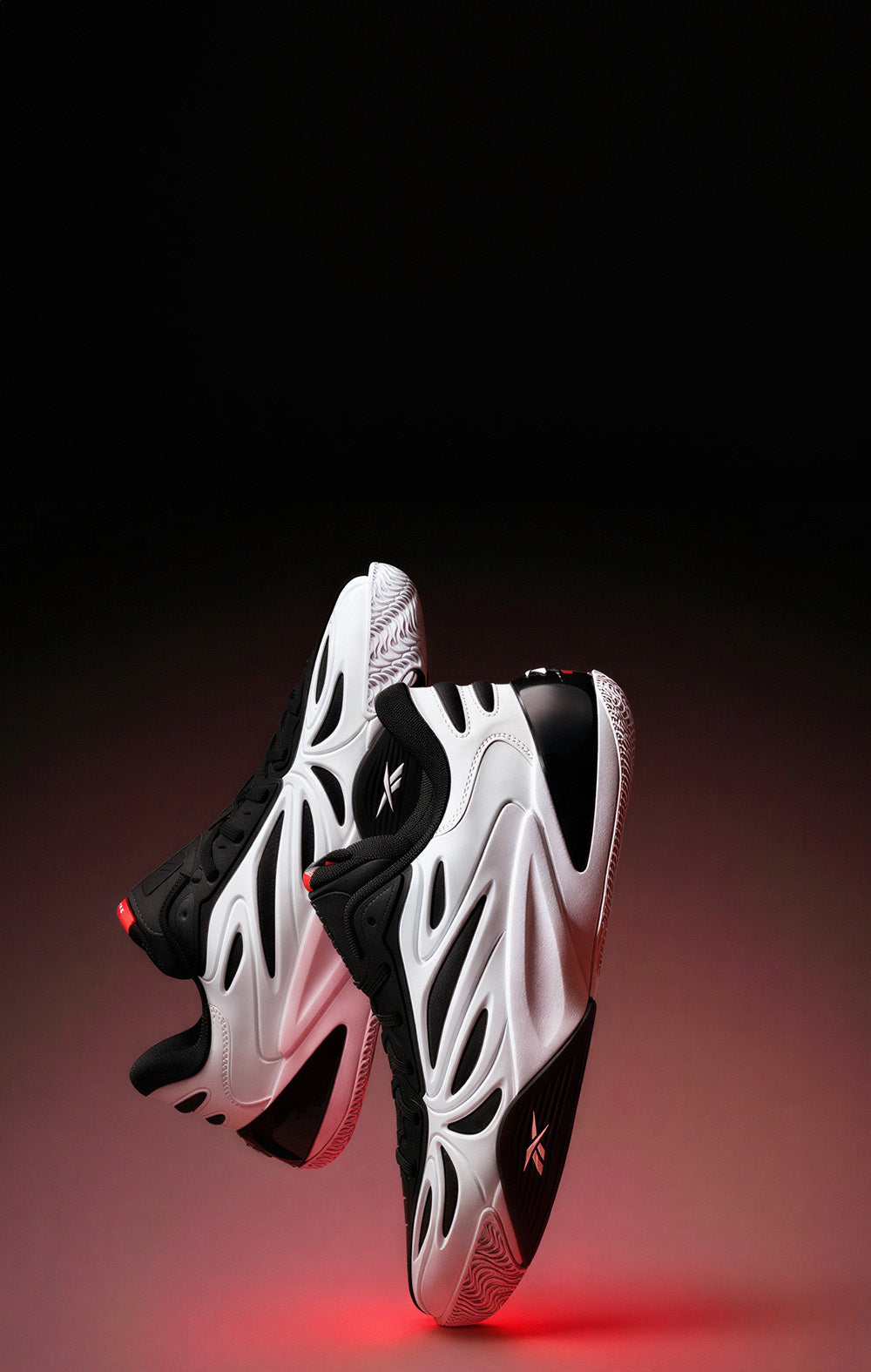 White and black athletic shoes with red accents on a dark background