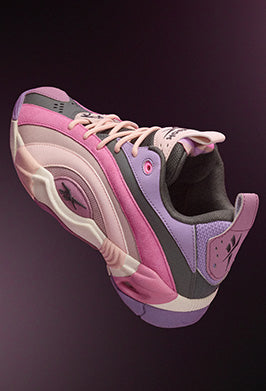 A stylish sneaker in shades of pink, purple, and gray with a wave-like design and light pink laces, set against a dark gradient background.