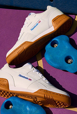 White Reebok sneakers with brown soles on a purple surface