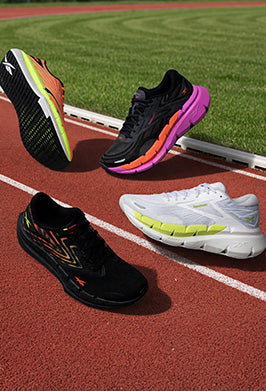Four running shoes on a track with grass in the background