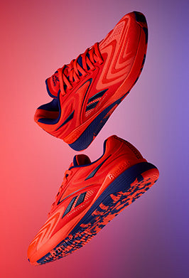 Red running shoes with black accents on a gradient background