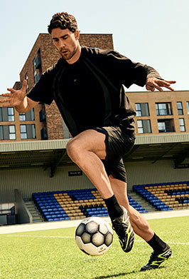 Man playing soccer on a field with stadium seats in the background