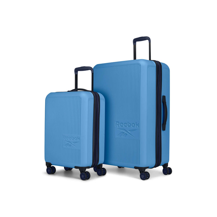 The Reebok Action Duo 2 Piece Luggage Set includes two blue hard-shell spinner suitcases with navy handles and trim, featuring the embossed Reebok logo on the front, shown upright on a white background.