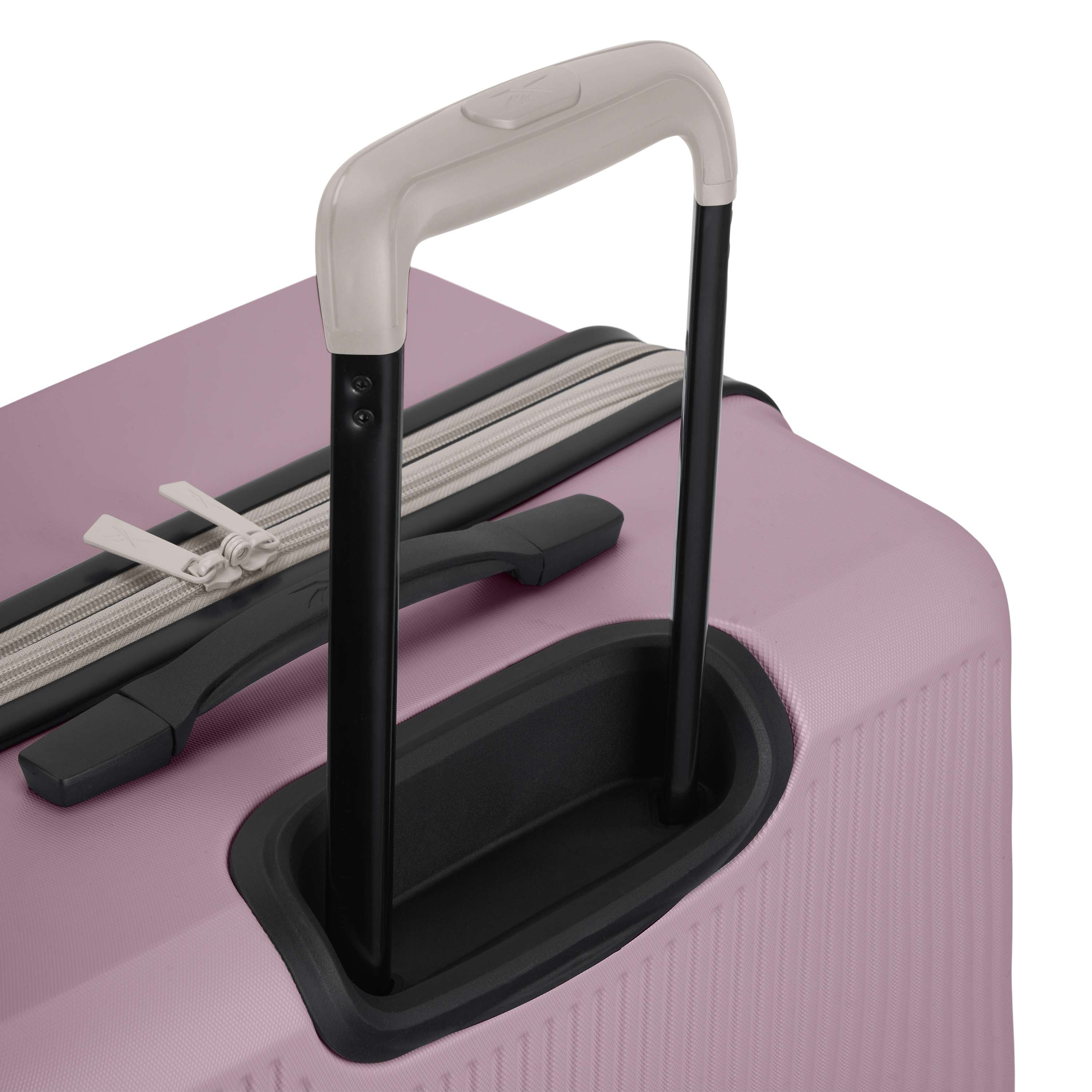 Close-up of the Reebok Action Duo 2 Piece Luggage Set in light pink, showing its black and white telescopic handle extended, spinner wheels, zipper closure, and built-in lock near the handle.