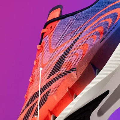 A close-up of a running shoe in bright orange and purple with black accents, shown against a solid purple background.