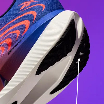 Close-up of a running shoe showing the side and heel area, with a blue and purple upper, orange graphic pattern, white midsole, and black outsole on a purple background.