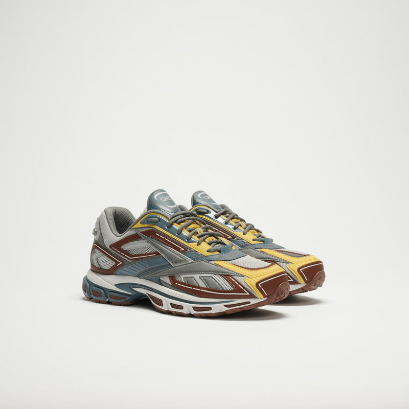 Reebok Premier Road Ultra LTD Shoes featuring a multicolor design—gray, yellow, blue, and brown accents—highlight the brand's archival running sneaker style on a plain white background.