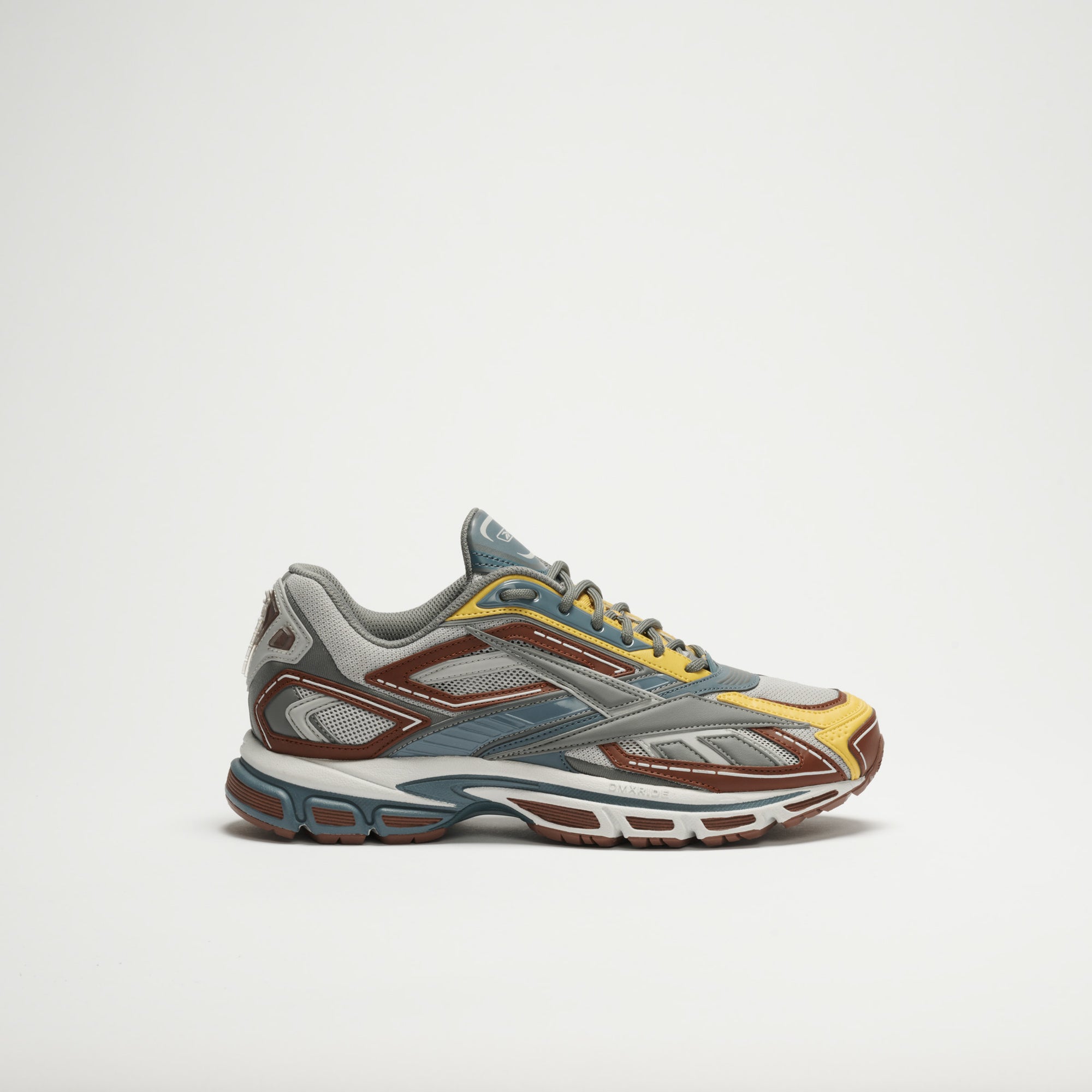 The Reebok Premier Road Ultra LTD Shoes showcase a modern, layered design in grey, blue, brown, and yellow shades with a dual-density midsole. Displayed from the side on a plain white background.