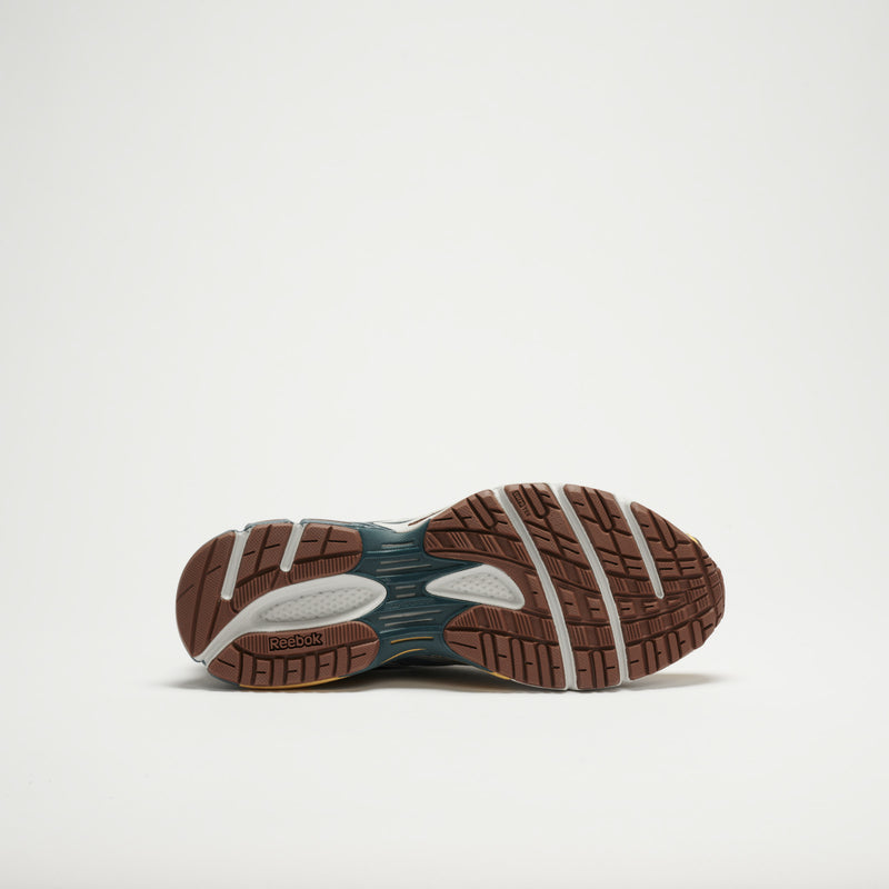 The image displays the sole of Reebok Premier Road Ultra LTD Shoes. It has a brown, traction-focused outsole with grooves, white and dark blue center accents, a dual-density midsole, and the Reebok logo by the heel.