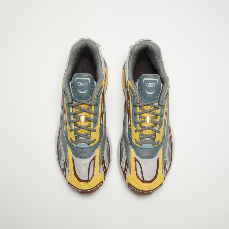 The Reebok Premier Road Ultra LTD Shoes, shown from above, feature yellow, gray, silver, and maroon mesh and leather details with gray laces and a dual-density midsole inspired by archival running designs.