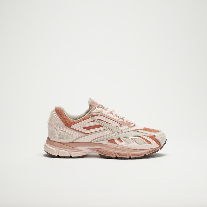 The Reebok Premier Road Ultra LTD Shoes feature pink and beige tones with light brown accents, a dual-density midsole, textured sole, and layered panels, shown against a plain white background.