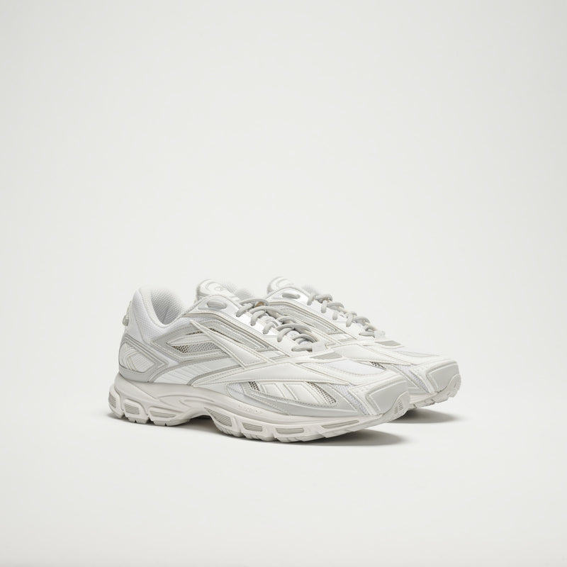 The Reebok Premier Road Ultra LTD Shoes are white athletic sneakers with silver accents, mesh and synthetic details, chunky textured soles, and a dual-density midsole, shown against a plain white background.