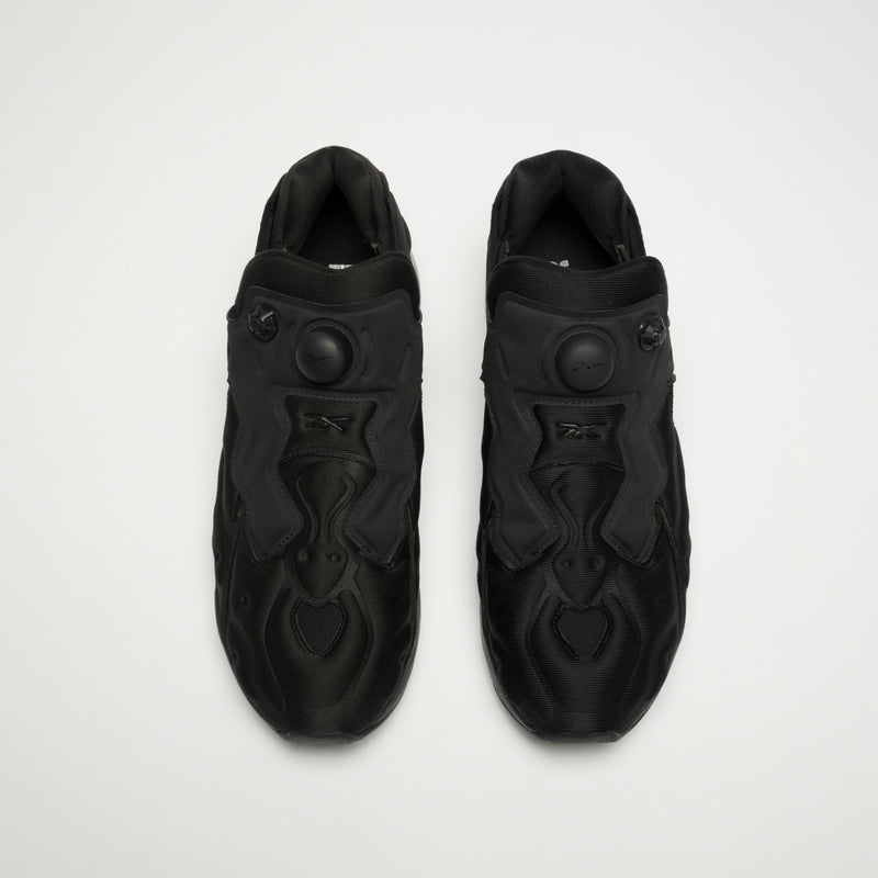 A pair of Reebok Instapump Sliver LTD Shoes is shown from above, with the left in solid black and the right in a lighter tone, both featuring a chunky design and pump buttons on the tongues for the air system.