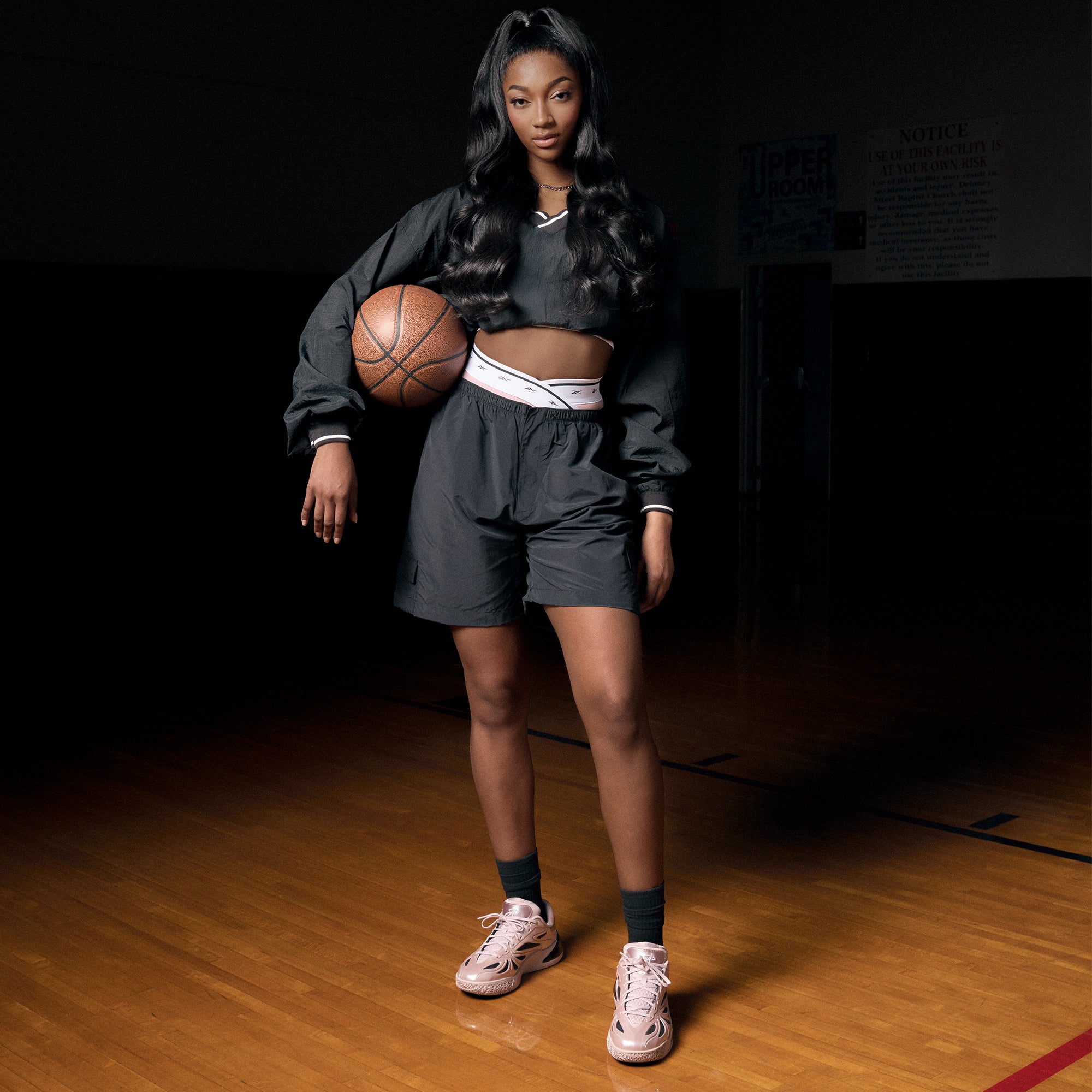Angel Reese holding a basketball on the court wearing the Rose Dust Angel Reese 1 Basketball shoes.,