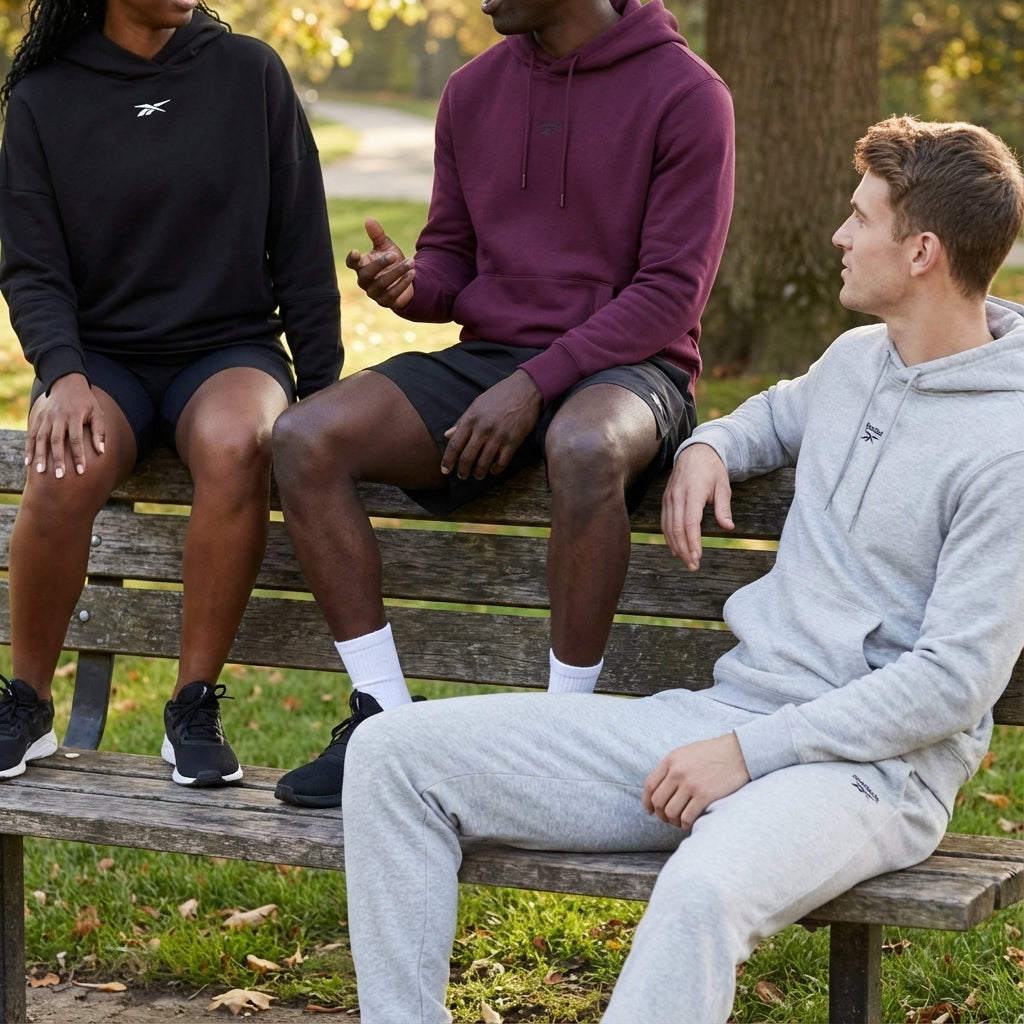 Three people sitting on a park bench conversing wearing athletic wear