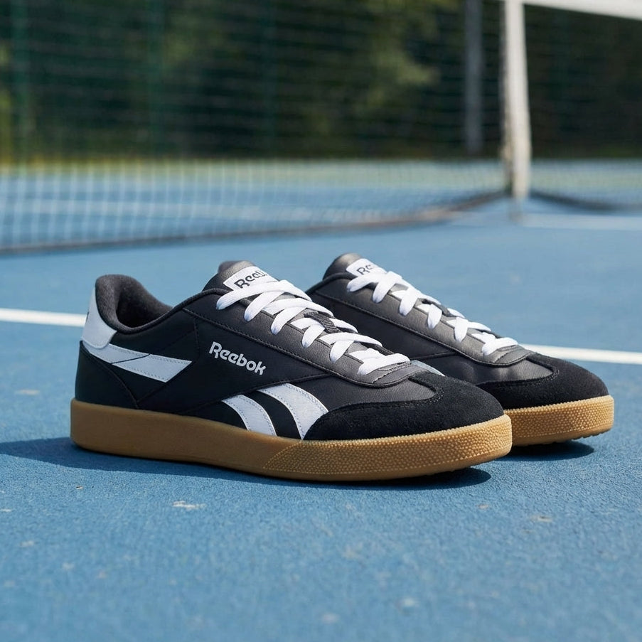 Black Reebok Smash Edge shoes on blue tennis court