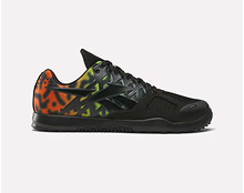 A black athletic sneaker with a glossy black Reebok logo and a colorful, gradient pattern in orange, yellow, and green on the heel and sides against a plain white background.