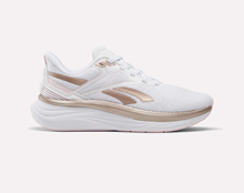 A white athletic sneaker with light pink and beige accents, featuring a mesh upper, lace-up closure, and a thick cushioned sole, displayed on a plain light background.