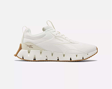 A white athletic sneaker with a chunky, segmented sole and tan accents, viewed from the side against a plain background.