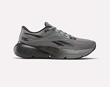 A gray athletic running shoe with black accents, featuring a thick, textured black sole and lace-up closure, shown in a side profile on a plain light background.