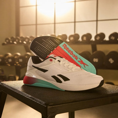 White Reebok sneaker with colorful accents on a black surface in a gym setting