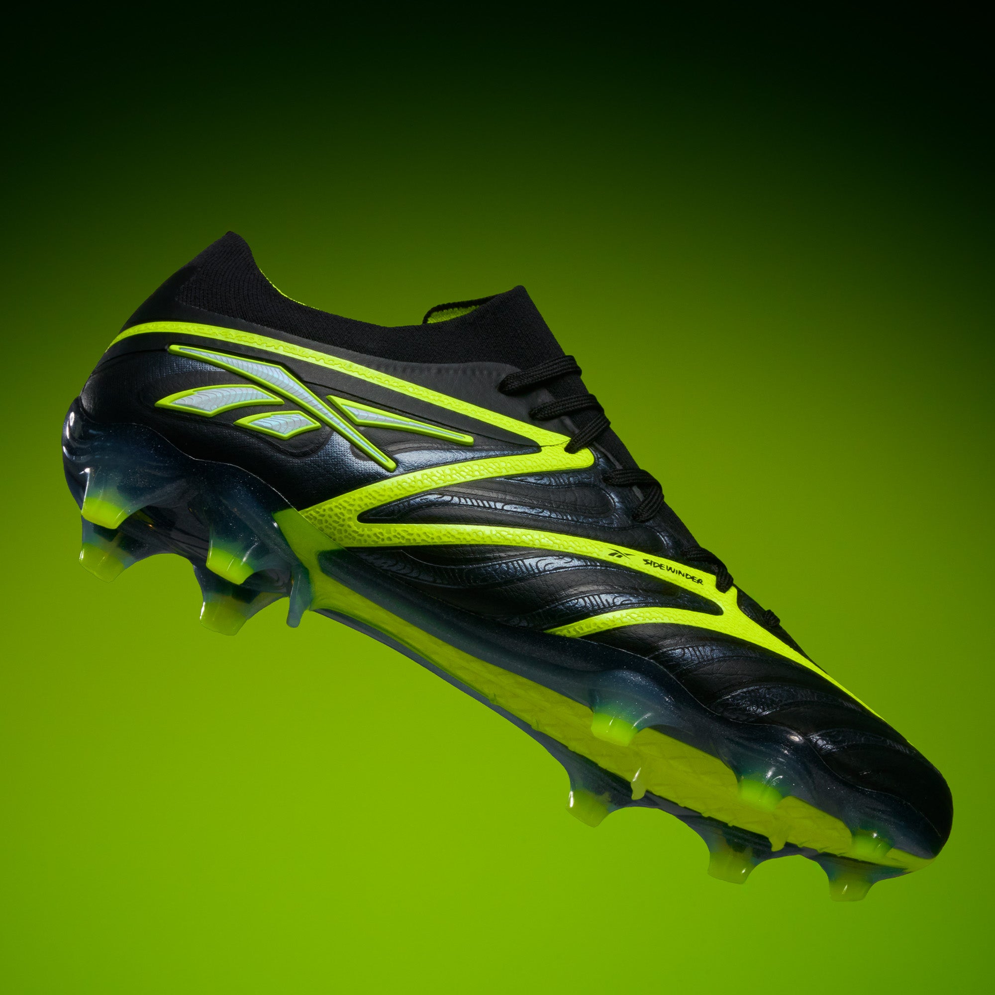 The Reebok Sidewinder 26 Elite FG Cleats, featuring a black design with bright yellow accents and neon yellow studs for firm grass, are presented on a gradient green background to showcase their sleek, modern look.