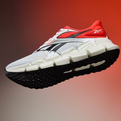 White running shoe with red and black accents on a gradient background
