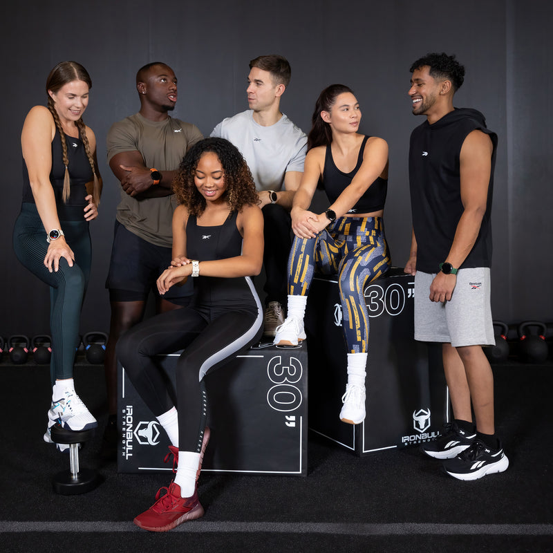 Group of people posing with fitness equipment in a gym setting