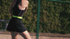a woman wearing black tennis dress playing tennis on a court surrounded by trees