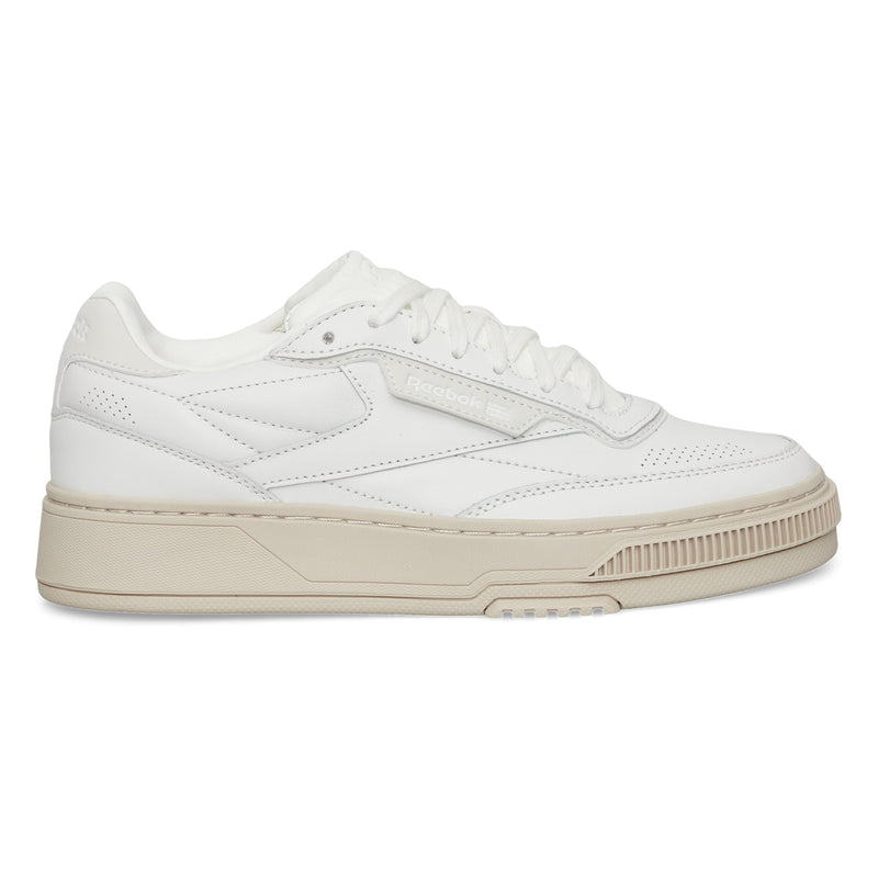 The Reebok Club C LTD Shoes are white low-top sneakers with a beige sole, perforated details, and white laces, shown in a side profile view—a timeless lifestyle classic inspired by tennis heritage.