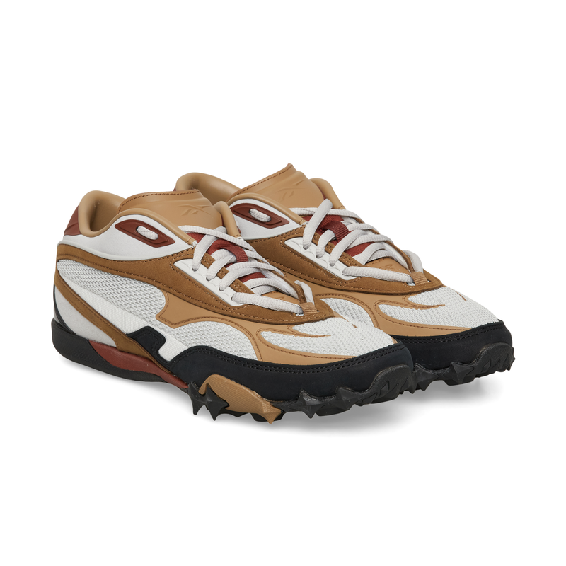 Reebok Spike Racer low-top lifestyle shoe with a white mesh upper, tan leather overlays, and a lugged black rubber outsole.