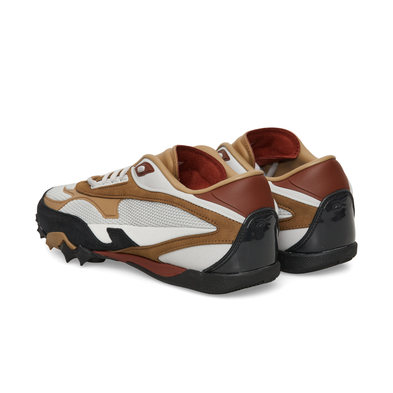 A pair of white, brown, and black Reebok Spike Racer track spikes viewed from the side and back.