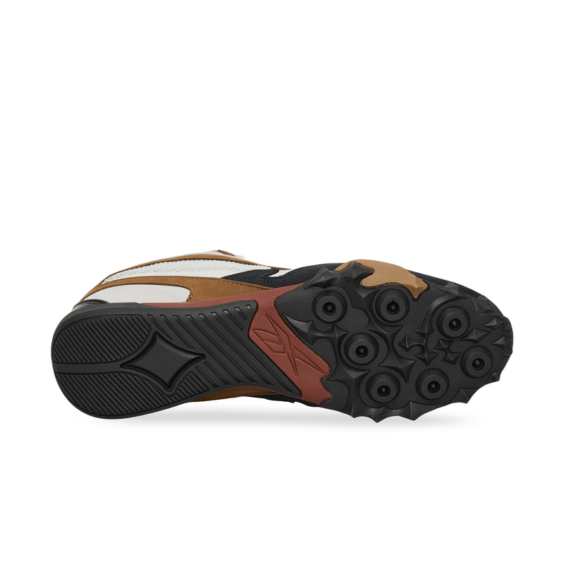 Black, brown, and white Reebok Spike Racer viewed from the sole, featuring a textured rubber tread pattern.