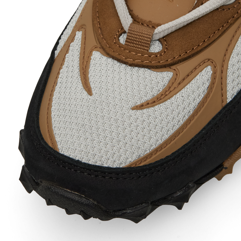 Close-up of a brown, tan, and light gray Reebok Spike Racer, featuring a black mudguard and a lugged, spiked rubber sole.