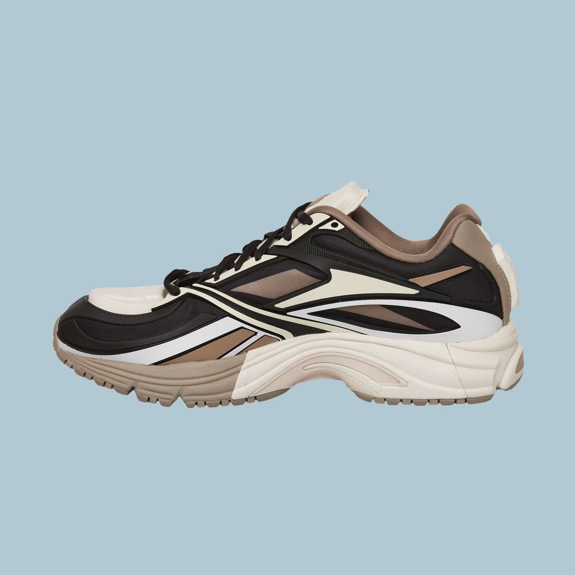 A side view of the Reebok Premier Road Modern Shoes showcases a layered, multi-colored design with black, white, beige, and brown accents, chunky sole, and modern style set against a light blue background.