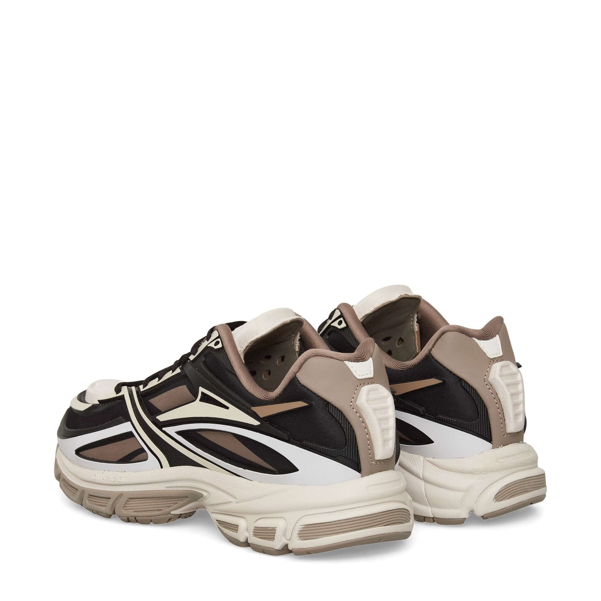 A pair of chunky sneakers in black, beige, and white with bold, angular designs on the sides, thick soles, and cushioned heels, shown from the back and side on a white background.