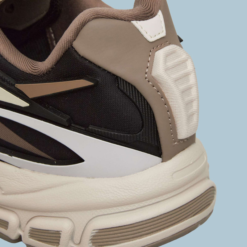 Close-up of the heel and sole of Reebok Premier Road Modern Shoes, showcasing black, tan, white, and beige textured layers against a light blue background.
