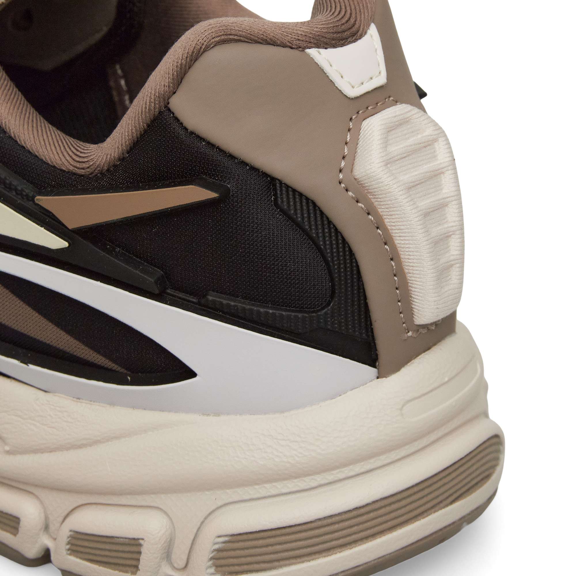Close-up of the heel area of a sneaker featuring black, brown, beige, and white colors, with textured and layered materials and a padded collar.
